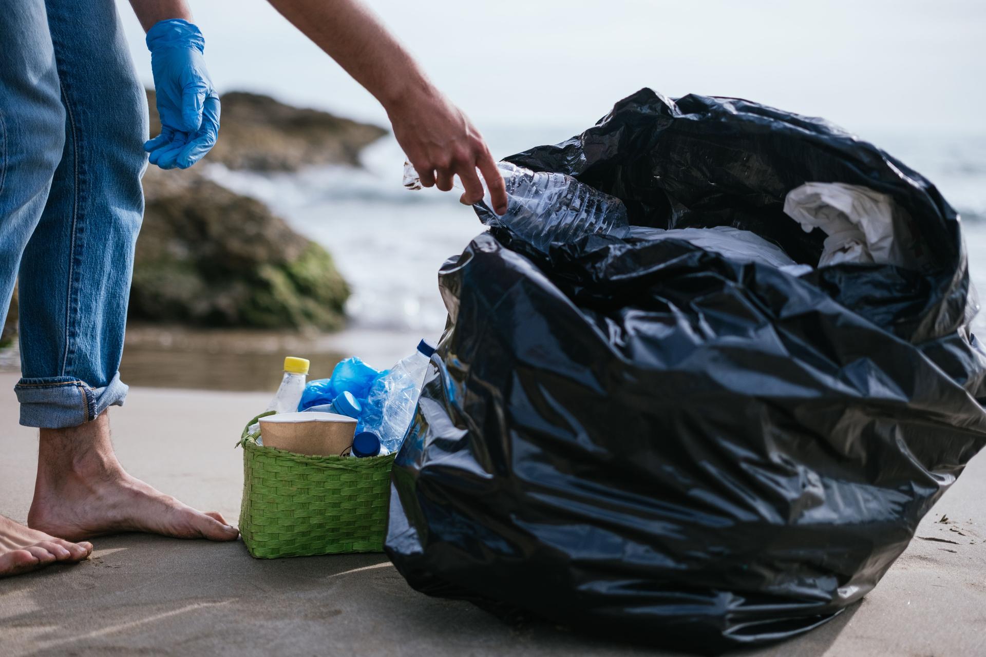 voluntario descalzo irreconocible recogiendo plástico y basura de la playa en su día libre. concepto de sostenibilidad y medio ambiente. conciencia y ecología. juntos podemos salvar el planeta.